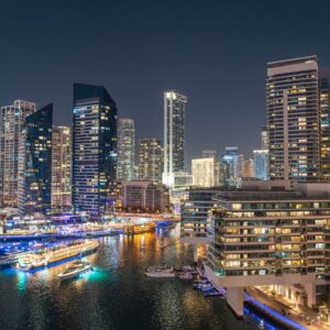 Stunning night view of Dubai Marina with illuminated skyscrapers and reflections on the water.