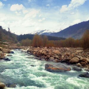 Beautiful mountain river flowing through a rocky valley with distant snowy peaks.